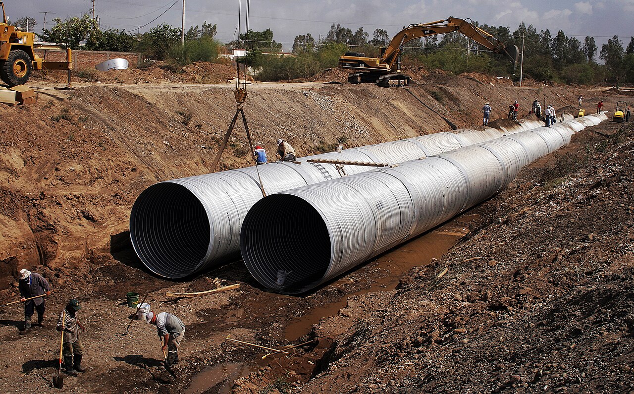Crew installing large-diameter sewer pipe in a trench