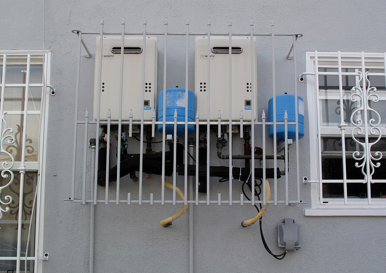 Two tankless water heaters installed on an exterior wall