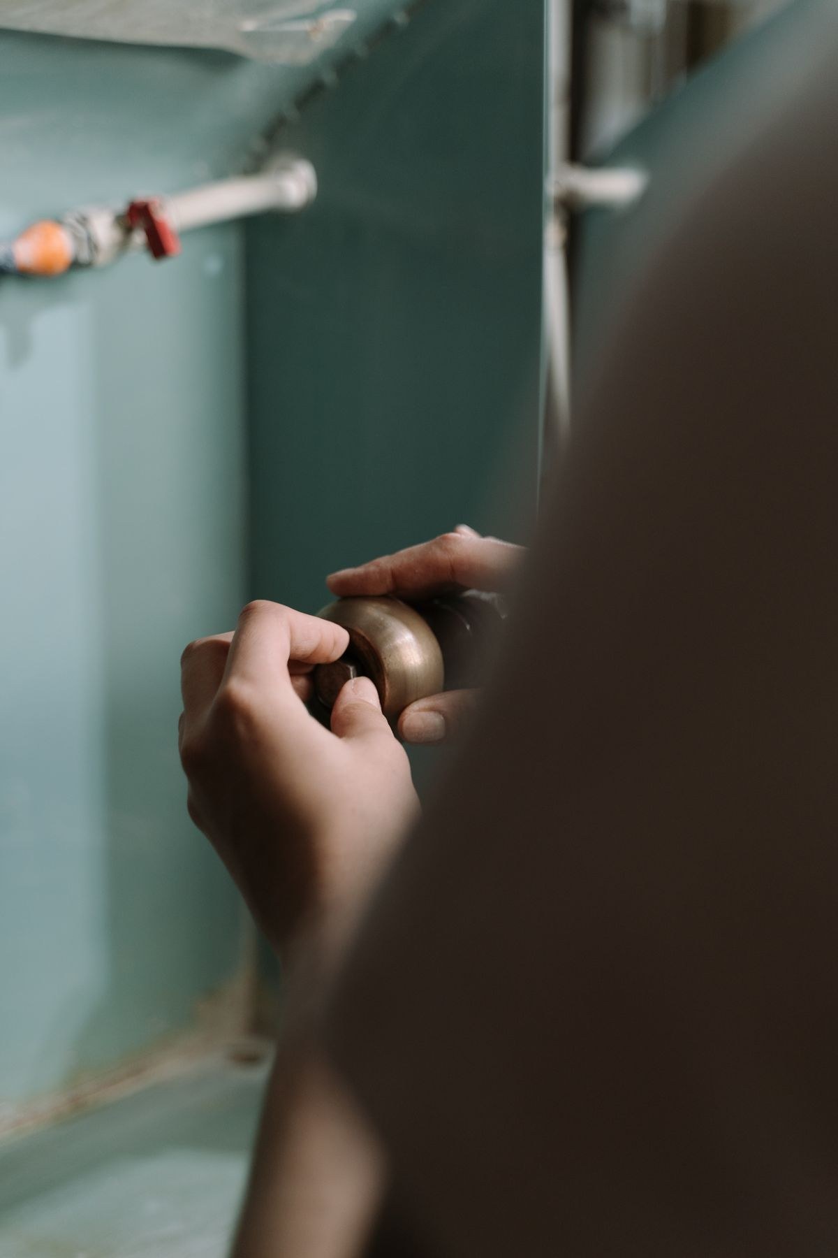 Hands repairing a plumbing fitting under a sink