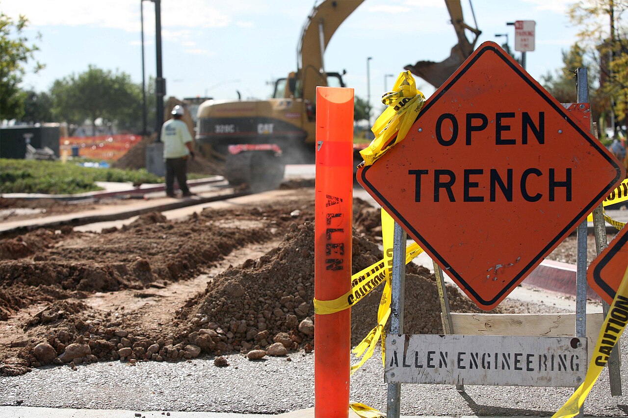 Open trench roadworks with an excavator on a job site
