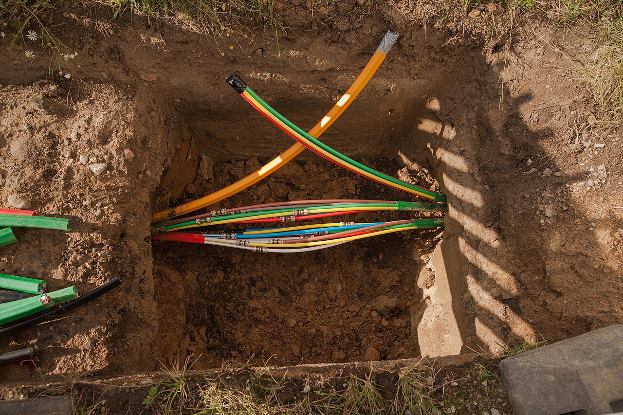 Colored utility lines crossing in an excavated pit